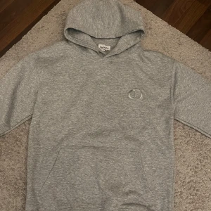 CD hoodie - Säljer en grå hoodie från CD med logga på bröstet. Tröjan har huva och en stor magficka framtill. 10/10 skick använd en gång hör av er vid minsta fundering. OBS STORLEK XL MEN SITTER SOM M