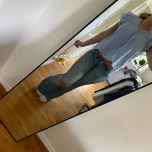 Ljusblå blus från Gina Tricot - Säljer en söt ljusblå blus från Gina Tricot med volangdetaljer på axlarna och liten v-ringning med knapp framtill. Blusen är luftig och har korta ärmar, perfekt för varmare dagar. Säljs för att den inte kommer till användning🩵