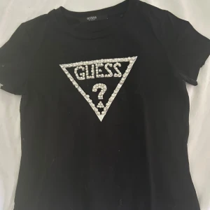 Guess t-shirt - Svart guess tröja i xs men den passar även S, det är en diamant som har lossnat men utöver det så är det en fin och skön tröja