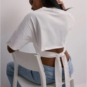 Vit croppad t-shirt med knyt i ryggen - Säljer en vit croppad t-shirt med korta ärmar och snygg knytning i ryggen. T-shirten har en modern och trendig look, perfekt till vardagstillfällen eller fest.💞💞