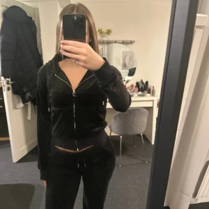 svart set från Juicy Couture - Säljer mitt set från Juicy Couture. Tröjan har dragkedja framtill, huva och ribbade muddar. Klassisk och stilren modell som är superbekväm och passar perfekt till vardagslooken. byxorna har fickor där bak och är supersköna! 