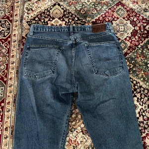 Polo Ralph Lauren ljusblå  jeans - Vintage blå Polo Ralph Lauren jeans med raka ben och femficksmodell. Byxorna har knappgylf och läderpatch bak i midjan. Perfekta för dig som gillar tidlös denimstil.