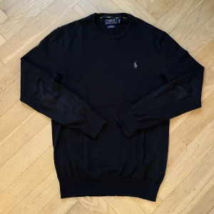 Svart Ralph Lauren Tröja - Säljer en stickad långärmad tröja från Polo Ralph Lauren med broderad logga på bröstet. | Tröjan är i tunn bomull och har rund halsringning  | Skick: 8/10 | Storlek: XS (passar dig runt 170) | Pris: 599 kr | Skriv vid minsta fundering!☺️