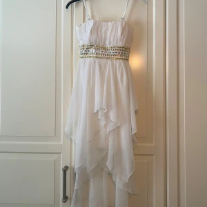 Vit klänning med pärldetaljer från Eva & Lola - Säljer en vit klänning från Eva & Lola med pärl- och paljettbälte i midjan. Perfekt till sommar eller avslutning. 