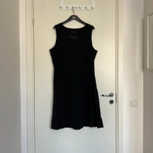 Svart ärmlös klänning från Classic Woman by Ellos - Klassisk svart ärmlös klänning från Classic Woman by Ellos. Klänningen har en enkel, tidlös design med rund halsringning och lätt utställd kjol. Perfekt basplagg att styla på många olika sätt.