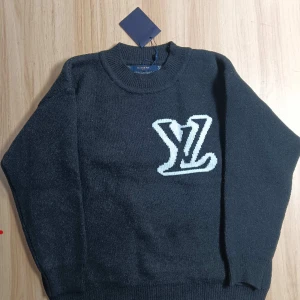 Svart stickad tröja Louis Vuitton M - Svart stickad tröja från Louis Vuitton med stor vit LV-logga både fram och bak. Tröjan har rund halsringning och långa ärmar. Perfekt för dig som vill ha en lyxig och stilren look med streetkänsla.
