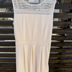 Vit klänning med spets från Kaffe - Superfin vit klänning från Kaffe med snyggt spetsmönster upptill och markerad midja. Klänningen har ärmlös design och lätt utställd kjol, perfekt för sommarens alla tillfällen. Enkel men ändå elegant look!