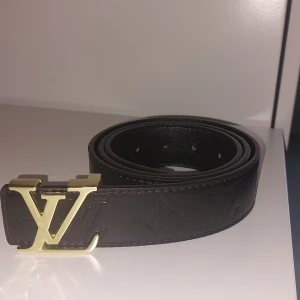 Lvbälte - Snyggt svart skärp från  i skinn med präglad -logga och ikoniskt -spänne i matt svart metall. Bältet har diskreta monogramdetaljer längs hela remmen och stilrena sömmar. Perfekt accessoar för att lyfta din outfit.
