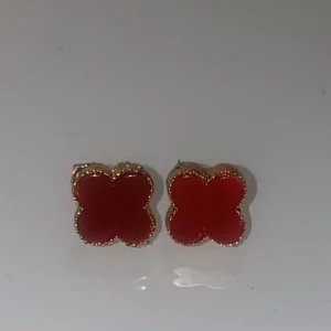 Röda fyrklöver örhängen med guldkant - Supersöta örhängen i form av röda fyrklöver med guldfärgad kant. Perfekta för att ge din look en färgklick och lite extra charm. Små och stilrena, passar till alla tillfällen när du vill sticka ut lite extra. Aldrig använda 