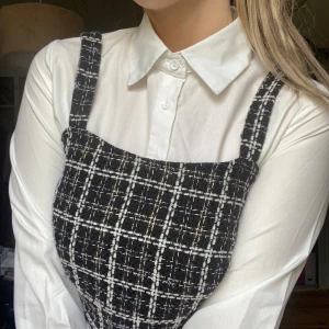 Vit klassisk skjorta med krage - Snygg vit skjorta med klassisk krage och knappar framtill. Skjortan har lång ärm och är tillverkad i ett slätt tyg som ger en clean och stilren look. Perfekt att styla under klänningar eller västar för en trendig layering-effekt.