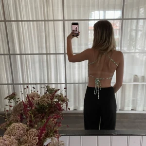 Grön zebramönstrad halterneck topp - Säljer en snygg halterneck topp med grönt och vitt zebramönster. Toppen har tunna band som knyts i nacken och ryggen, vilket ger en öppen rygg och trendig look. Perfekt för varma dagar och sommarens alla äventyr.
