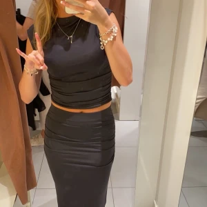 Svart croppad topp med tight passform - Säljer min fina mörk gråa Gina kjol som sitter som en smäck och bra i längden till mig som är 165 cm🙏🏼🙏🏼❤️