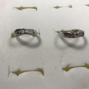 925 Silverpläterade Par Ringer med LOVE-text och stenar - Två stilrena Silverpläterade ringar med texten 'LOVE' ingraverad och små glittrande stenar på ovansidan. Ringarna har en modern, något bredare design och passar perfekt för dig som gillar detaljer med budskap. Helt ny, stämplade 
