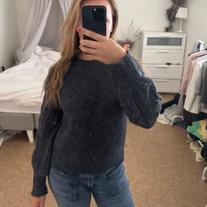 Mörkblå stickad tröja med mönstrade ärmar - Mysig mörkblå stickad tröja med unika mönstrade ärmar i hålstickat. Tröjan har rund halsringning och ribbade muddar vid ärmslut och nederkant. Perfekt att slänga på sig på sommaren. Nopprig men fixar vid intresse 