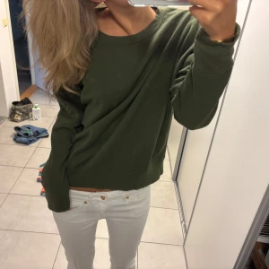 Olivgrön sweatshirt i bomull - Enkel och snygg olivgrön sweatshirt med rund halsringning och långa ärmar. Tröjan har en relaxed passform och är tillverkad i mjuk bomull, perfekt för chill dagar. Passar dig som gillar en clean och stilren look.