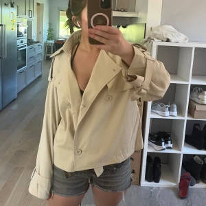 Beige trenchcoat - Säljer denna trenchcoat då jag inte tycker att den passar mig. Den är helt ny! Endast använd en gång. Den är tunn så den passar super bra till sena/kyligare sommar dagar/kvällar. 