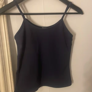 Mörkblå linnetopp från Stick Man - Säljer en stilren mörkblå linnetopp från Stick Man. Toppen har tunna axelband och en enkel, clean design som är lätt att matcha. Materialet känns mjukt och följsamt mot huden. Perfekt för dig som gillar minimalistisk stil. Storleken står inte men skulle gissa på att den är i xs.