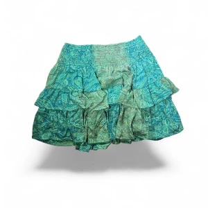 Turkos volangkjol  - Superfin kort kjol i turkos och grönt med paisleyinspirerat mönster. 90% silke!  Midjemått är 27 cm men midjan är stretchig och den är 37cm lång.💚