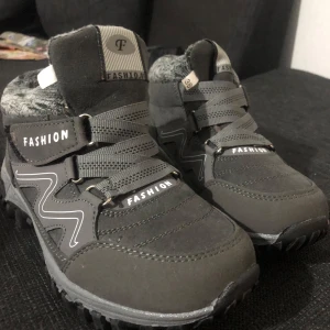 Grå boots med fuskpälsfoder - Helt nya Snygga grå boots med grov sula och mjukt fuskpälsfoder. Skorna har breda snören, kardborreband med texten 'FASHION' och dekorativa vita detaljer på sidorna. Perfekta för kyliga dagar och ger en sportig look. Storlek: 36