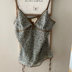 Topp i 100% silke från Ambercombie - Den finaste linnetoppen från Abercrombie & Fitch i 100% silke (se lapp på sista bild). Toppen är ljusblå och brun med justerbara axelband, v-ringning och små knytrosetter i sidorna. Säljes då den är för liten för mig i bysten😔🫶 Passar A/B-kupa