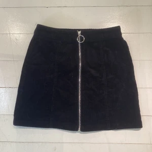 Svart manchesterkjol från FB Sister - Svart kortkjol i manchester från FB Sister som sitter som en smäck. Storlek S.