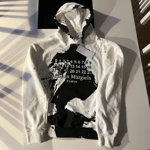 Maison Margiela Hoodie - Säljer min feta Maison Margiela Paint-splash 🎨 hoodie då den aldrig kommit till användning! Storlek M, Nyskick med tagsen kvar på tröjan, pris går diskuteras vid snabb affär! Hör av er vid minsta fundering! 