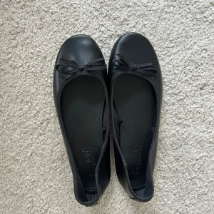 Svarta ballerinaskor med rosett - Säljer dessa ballerina skor med rosett framtill. Jättefina och sköna! Använda ett fåtal gånger