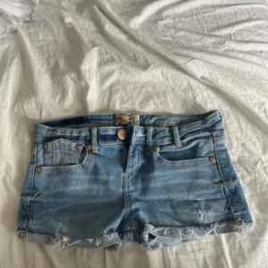 Ljusblå low waist jeansshorts  - Snygga ljusblå jeansshorts. Shortsen har normal passform, knapp och dragkedja framtill samt detaljerade sömmar och nitar. Perfekta för sommardagar och festivalhäng. Dom är knappt använda och är i jätte bra skick. Skriv vid fråger💗