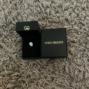 Silverörhänge Alien Maria Nilsdotter - Unikt örhänge i silver från Maria Nilsdotter med ett coolt alienansikte. Kommer i original ask. Perfekt för dig som vill sticka ut med en lekfull och edgy detalj i din stil.