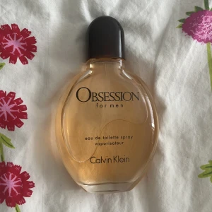Obsession for Men parfym Calvin Klein - Obsession for Men från Calvin Klein är en klassisk eau de toilette med varm, bärnstensfärgad vätska i en rundad glasflaska. Flaskan har svart plastkork och tydlig logga framtill. En ikonisk herrdoft som känns både tidlös och självsäker. Väldigt unisex med en ren doft 