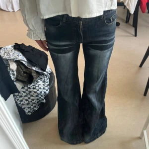 Mörkblå bootcut jeans från Sisters - Säljer ett par mörkblå bootcut jeans från Sisters med snygga slitningar och ljusa partier på låren. Jeansen har låg midja och vida ben. .