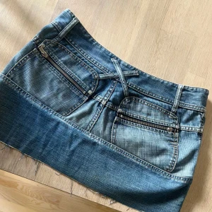 Diesel Jeanskjol - Cool jeanskjol från Diesel i blå denim med slitna detaljer och fransig nertill. Storlek 28, midjemått rakt över: 39cm. Hör av er vid frågor! 