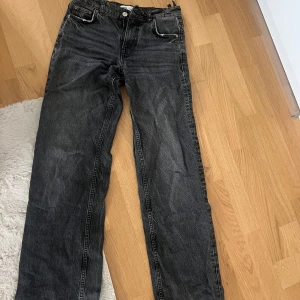 Svarta raka jeans från Zara - Säljer ett par svarta jeans från Zara i rak modell. Jeansen har klassisk femficksdesign, normalhög midja och är tillverkade i bomull. Snygg tvättad look som passar till allt och ger en cool vibe.