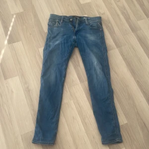 Replay blå jeans med slitningar - Säljer ett par blå jeans från Replay med snygga slitningar och klassiska detaljer. Jeansen har raka ben, fem fickor och tydliga sömmar. Materialet är jeans i bomull och passformen är normal. Perfekta för en avslappnad och cool stil. Jeansen är sparsamt använda, och är i storleken 30/32, men passar mer som 29/30. Jeansen har blivit för små på mig och säljer nu dessa för ett otroligt fint pris: 350 kr. Hör av er vid minsta fundering eller fler bilder!  