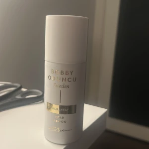Bobby Oduncu Hårspray 100ml - Bobby Oduncu Hårspray i vit och guld design, 150 ml. Ger stark stadga och håller frisyren på plats hela dagen. Snygg och stilren flaska, perfekt att ha med i väskan för snabba touch-ups. Svenskt märke med fokus på hårvård och styling.