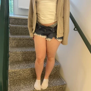 Mörkblå jeansshorts med spetskant - Snygga mörkblå jeansshorts med vit spetskant längst ner. Hög midja igentiligen men om du viker ner dem så får du en lågmidjad och trendig look. Matrialet är ett stretchigt jeanstyg. ❤️