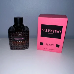 Valentino Donna Born In Roma Intense - Valentino Donna Born In Roma Intense EdP, 100 ml. Flaskan är mörk och har ett coolt nitat mönster i glaset med svart kork. Kartongen är starkt rosa med svarta detaljer och tydlig logga. En lyxig och modern parfym som sticker ut i badrumshyllan.