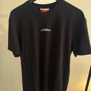 Svart t-shirt med grafiskt tryck från Zara - Svart t-shirt från Zara oversize med coolt grafiskt tryck i rosa, rött, blått och orange på ryggen samt texten 'WE NEED ART IN OUR LIVES' fram. Klassisk passform och rund hals. Perfekt för dig som gillar statement-plagg och färgklickar i din outfit.