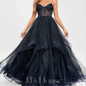 Glittrig marinblå balklänning JJ's House - Magisk marinblå långklänning från JJ's House med glittrigt tyg, smala axelband och snörning i ryggen. Klänningen har en voluminös kjol i lager på lager och markerad byst med meshdetaljer. Perfekt för bal eller festkvällar när du vill sticka ut. Klänningen är använd 1 gång. Jag är 163cm lång och den sitter perfekt