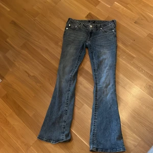 True Religion bootcut jeans blå, stl 27 - Säljer ett par blå jeans från True Religion i lowrise flare . Jeansen har fem fickor, snygga kontrastsömmar och låg midja. Materialet är jeans i bomull med en lätt tvättad look. De är slitna i hälarna men det är inget man tänker på. Säljer då de är för stora. Pris kan diskuteras 
