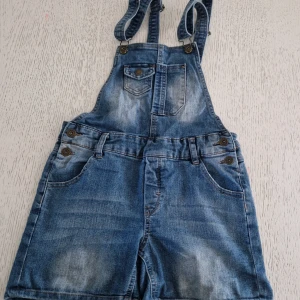 Hängsleshorts i jeans strl 146 - Snygga blå jeansshorts med hängslen från LTB Industries. Klassisk denimlook med justerbara axelband, flera fickor fram och bak samt coola knapprader i sidorna. 