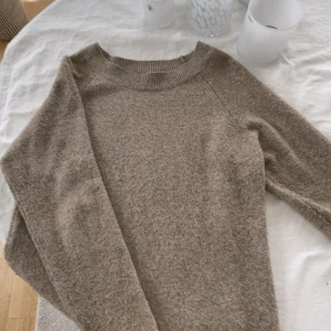 Beige stickad tröja vero moda - Mysig beige stickad tröja med rund halsringning och långa ärmar. Perfekt för lager på lager och chill dagar. Den har en enkel och stilren look som funkar till det mesta och är superbekväm tack vare det stickade materialet.