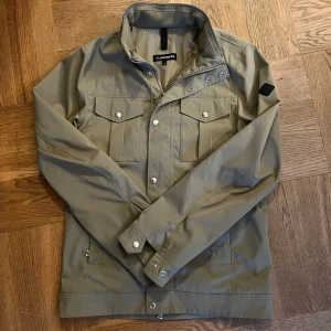Khaki grön vindjacka( Bailey) från J.Lindeberg -  J.Lindberg vindjacka från märket Bailey som har väldigt mycket kvar att ge. jackan är bara använd ett fåtal gånger Skriv om du har någon fråga 😊( ny pris 3.4) och jag är 185cm 