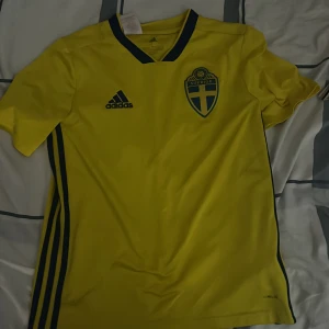 Svenska landslagets fotbollströja Adidas OBS köparen står för frakt  - Svensk herr landslags tröja ganska bra skick storlek L i barnstorlek. Köparen står för frakt eller mötas upp i centrala Göteborg. Den har ett litet tråd som sticker ut 