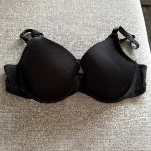 Svart BH från H&M 80C - •En klassisk svart BH från H&M i storlek 80C.  •Den har vadderade kupor, justerbara axelband och stängs med hyskor bak. •Sidorna är i mesh och materialet är mjukt och bekvämt, perfekt för dig som vill ha en enkel och stilren look. •Mycket bra skick. Tvättad. •Djurfritt och rökfritt hem.
