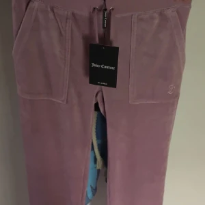 Ljusrosa mjukisbyxor Juicy Couture XXS - Supermjuka ljusrosa/ljuslila mjukisbyxor från Juicy Couture med stora fickor fram och bak, samt broderad JC-logga på ena fickan. De är perfekta för en chill och trendig look. Byxorna är aldrig använda. Nypris 1200kr, pris kan diskuteras.