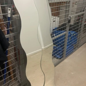Lång formad spegel, 2st - Bilderna visar en vågformad spegel i två delar, perfekt för att ge ditt rum en modern och trendig look. Monteringsdetaljer medföljer. Spegeln är idealisk för dig som vill ha en unik inredningsdetalj som sticker ut och passar perfekt i ungdomsrum eller lägenhet.
