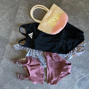 Badkläder barn/klädpaket 110/116 - Säljer en svart Adidas baddräkt, en zebramönstrad baddräkt (volang upptill/Lindex)och en ribbad bikini (Lindberg). Perfekt för stranden eller poolen! Baddräkten har sportig look, zebrabaddtäkten har trendigt mönster och den rosa bikinin har snygg ribbad struktur. Baddräkterna är i storlek 116 och bikini i 110/116. Somrig väska följer även med. 