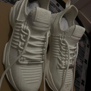 Vita chunky sneakers Steve Madden - Snygga helvita sneakers från Steve Madden med chunky sula och stickad ovandel. Skorna har coola detaljer som präglad logga, vita snören med svarta inslag och metalltips. Perfekta för dig som gillar en sportig och modern look. Dock har jag haft på mig den bara en gång, tog fel storlek. Men sen dess har jag ej använt de. 