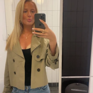 Beige croppad trenchcoat - Snygg croppad trenchcoat i beige med dubbelknäppning och stora svarta knappar🥰